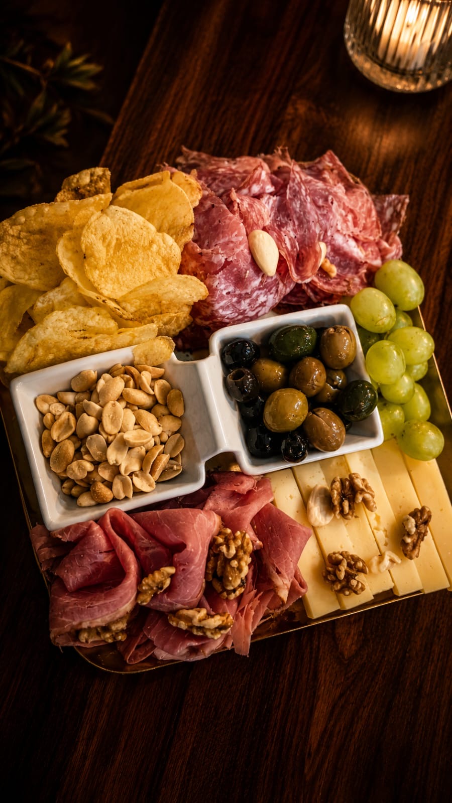 Tabla rectangular con salami, jamón, quesos, uvas y aceitunas