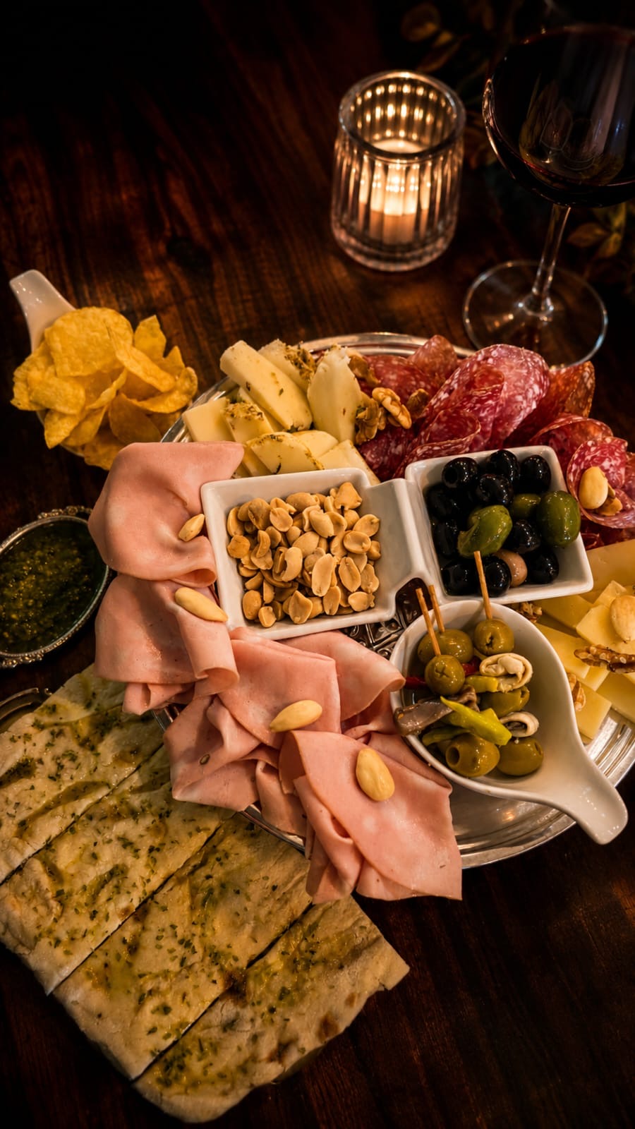 Tabla con mortadela, salami, quesos y aceitunas a la luz de las velas